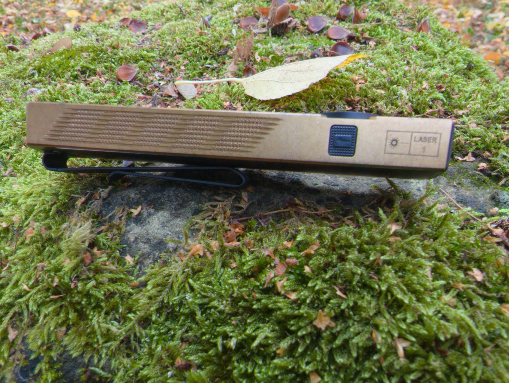 Tranche de l'Olight ArkPro Ultra avec le bouton laser dédié, le marquage Laser classe 1 et le grip strié