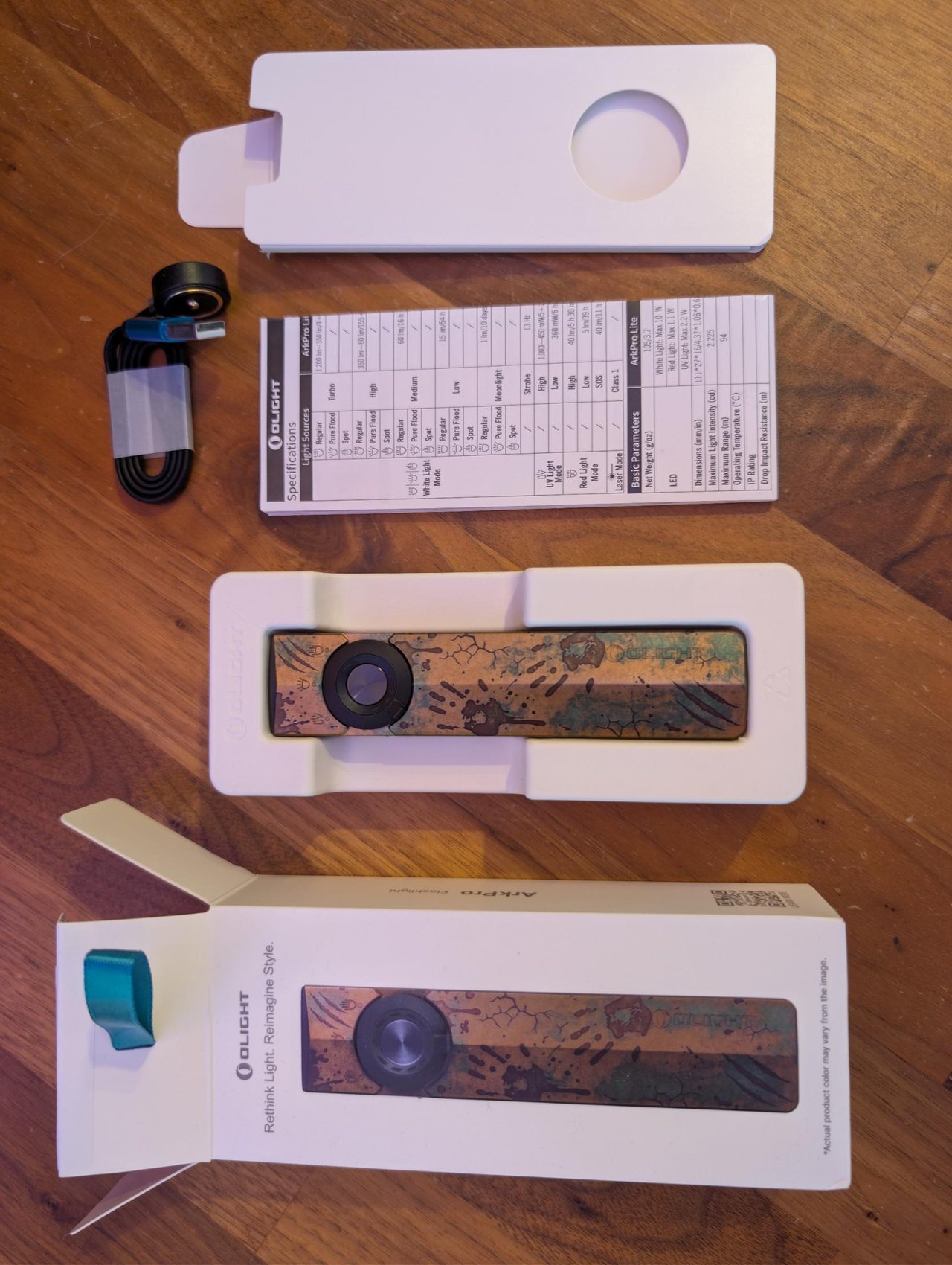 Unboxing Olight ArkPro Relique des terres désolées : boîte, lampe dans son calage, câble magnétique MCC et fiche des caractéristiques