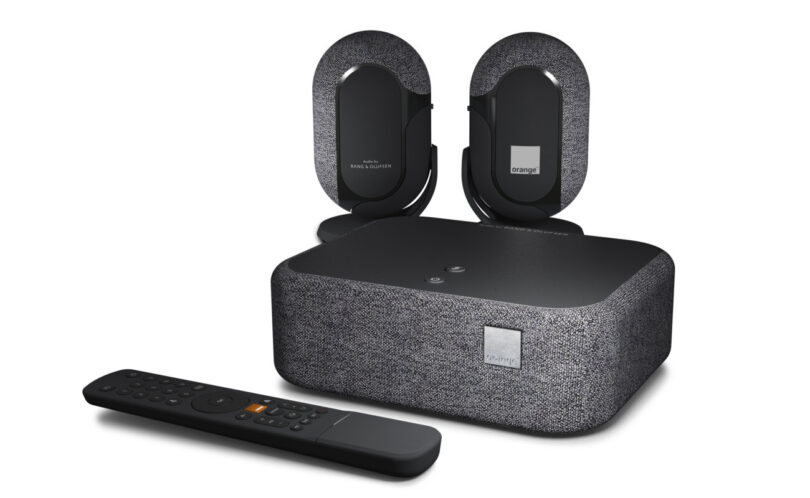 Le Décodeur Home Cinema d'Orange à revêtement tissu gris, ses deux enceintes sans fil Dolby Atmos FlexConnect signées Bang & Olufsen et sa télécommande