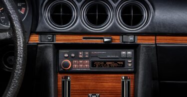 Autoradio rétro Pioneer SXT-C10PS installé dans la console centrale boisée d'une Mercedes 280 SL R107 de 1980, éclairage orange