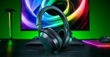 Casque gaming sans fil Razer Barracuda V2 Pro noir posé sur un bureau devant un écran coloré, avec clavier et souris Razer en arrière-plan