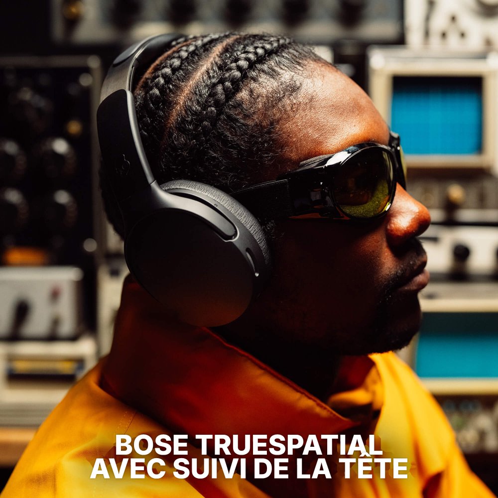 Homme en veste orange portant le casque Skullcandy Crusher 1080 ANC, avec la mention traduite Bose TrueSpatial avec suivi de la tête