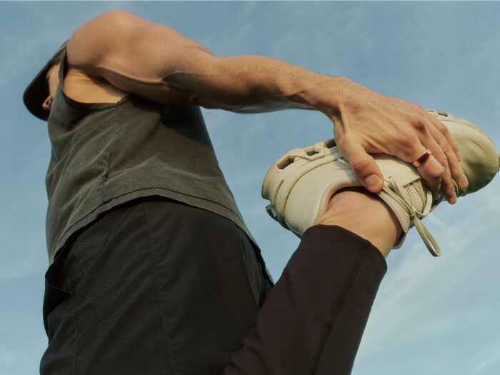 Un sportif s'étire en plein air avec une bague connectée Oura au doigt, la bague estime désormais le VO2 max à partir des sorties GPS
