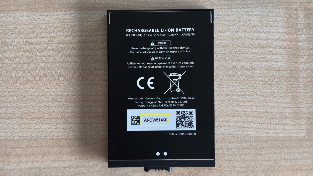 Batterie lithium-ion noire de la Nintendo Switch 2 à batterie remplaçable posée sur une table, avec son étiquette, ses marquages réglementaires et son numéro de lot