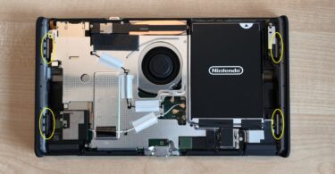 Console Nintendo Switch 2 à batterie remplaçable ouverte sur une table, coque arrière retirée, batterie noire et ventilateur visibles, aimants entourés en jaune par le guide officiel Nintendo