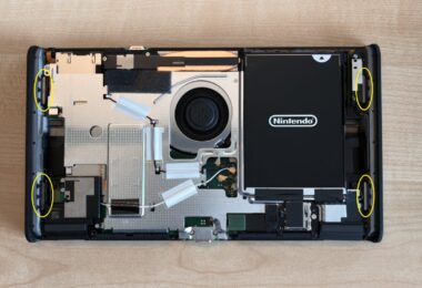 Console Nintendo Switch 2 à batterie remplaçable ouverte sur une table, coque arrière retirée, batterie noire et ventilateur visibles, aimants entourés en jaune par le guide officiel Nintendo