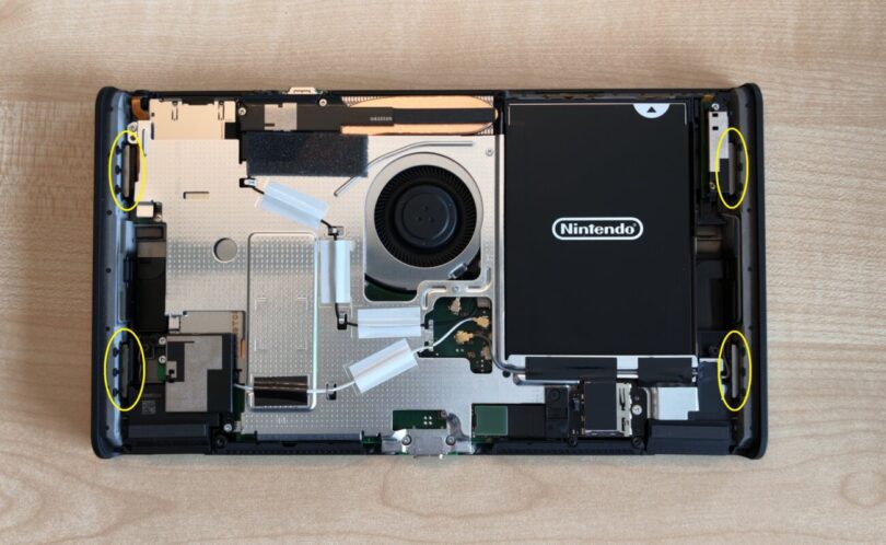 Console Nintendo Switch 2 à batterie remplaçable ouverte sur une table, coque arrière retirée, batterie noire et ventilateur visibles, aimants entourés en jaune par le guide officiel Nintendo
