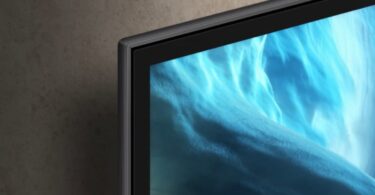Bord ultrafin d'un téléviseur OLED Samsung Vision AI 2026 fixé au mur, écran affichant des vagues bleues abstraites, illustration des TV connectées concernées par la question de la télémétrie