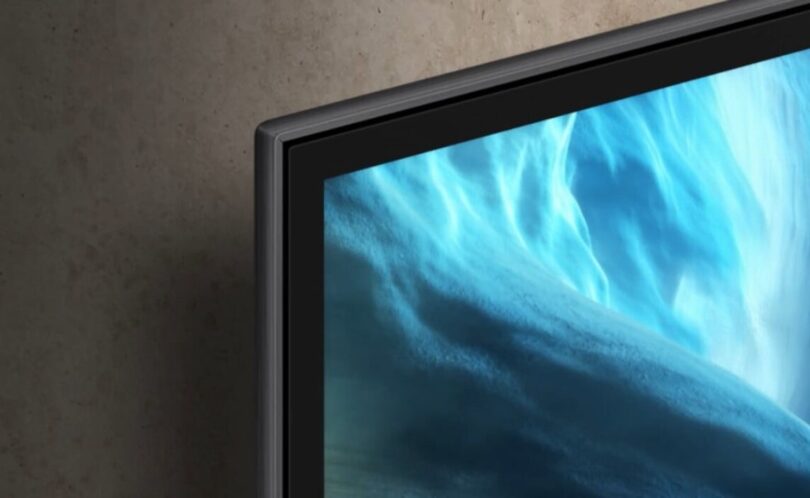 Bord ultrafin d'un téléviseur OLED Samsung Vision AI 2026 fixé au mur, écran affichant des vagues bleues abstraites, illustration des TV connectées concernées par la question de la télémétrie
