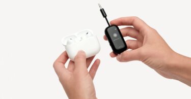 L'adaptateur Bluetooth Twelve South AirFly View noir tenu en main à côté d'un boîtier d'AirPods Pro, avec son écran qui guide l'appairage des écouteurs sans fil