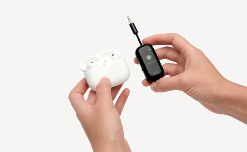 L'adaptateur Bluetooth Twelve South AirFly View noir tenu en main à côté d'un boîtier d'AirPods Pro, avec son écran qui guide l'appairage des écouteurs sans fil