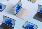 Plusieurs ordinateurs portables de différentes couleurs affichant le fond d'écran bleu de Windows 11, vus du dessus