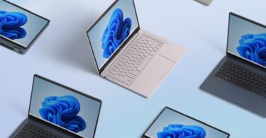 Plusieurs ordinateurs portables de différentes couleurs affichant le fond d'écran bleu de Windows 11, vus du dessus