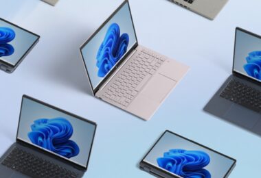 Plusieurs ordinateurs portables de différentes couleurs affichant le fond d'écran bleu de Windows 11, vus du dessus