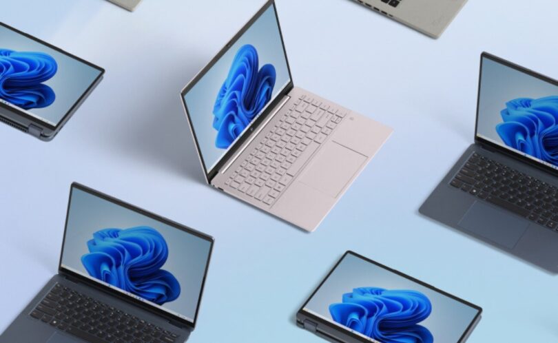Plusieurs ordinateurs portables de différentes couleurs affichant le fond d'écran bleu de Windows 11, vus du dessus