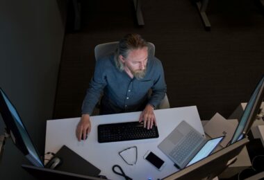 Un utilisateur devant un poste de travail Windows équipé de plusieurs écrans, d'un clavier et d'un ordinateur portable, illustration des mises à jour de sécurité Windows