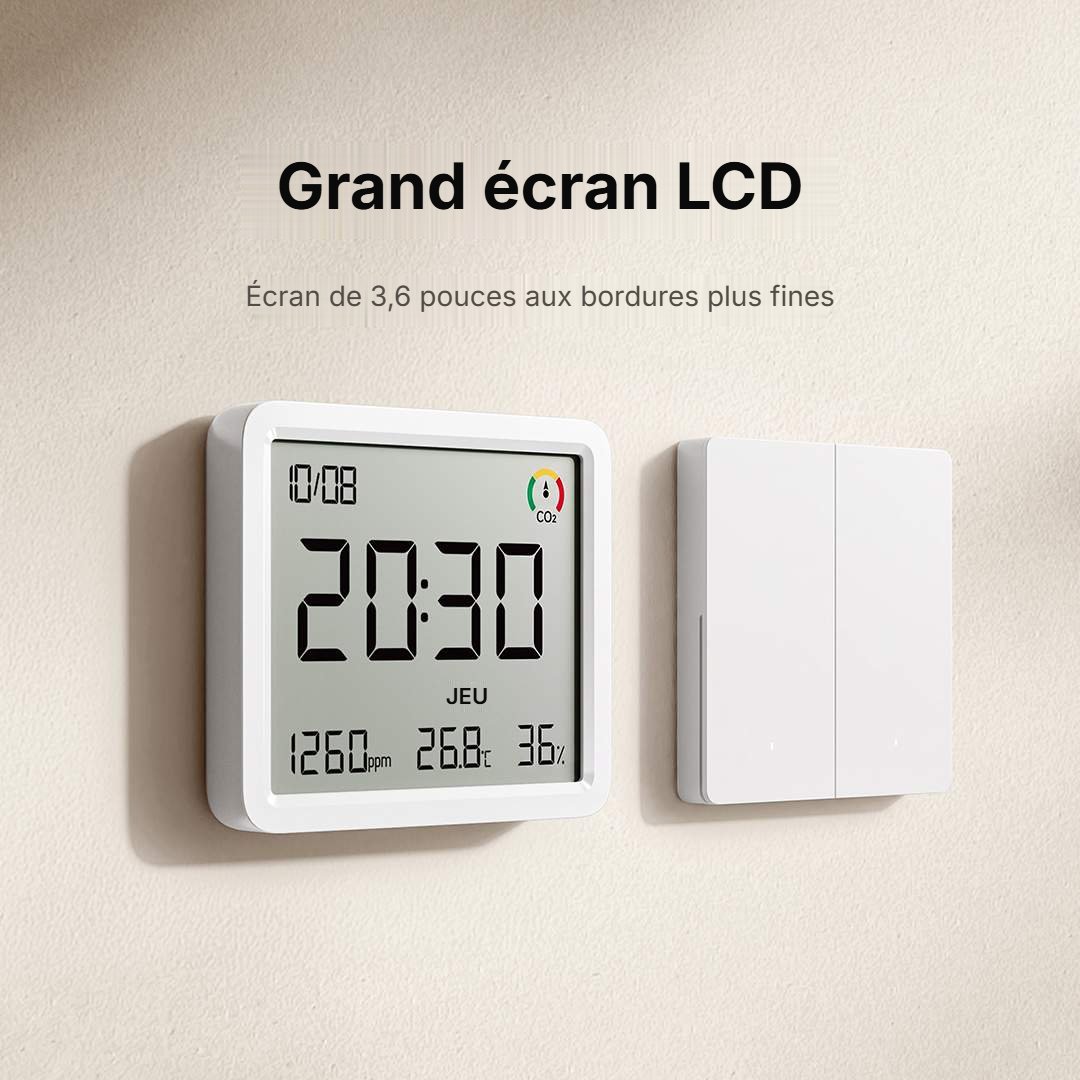 Xiaomi Monitor 3 Pro fixé au mur à côté d'un interrupteur, grand écran LCD de 3,6 pouces affichant l'heure, 1 260 ppm de CO2, la température et l'humidité